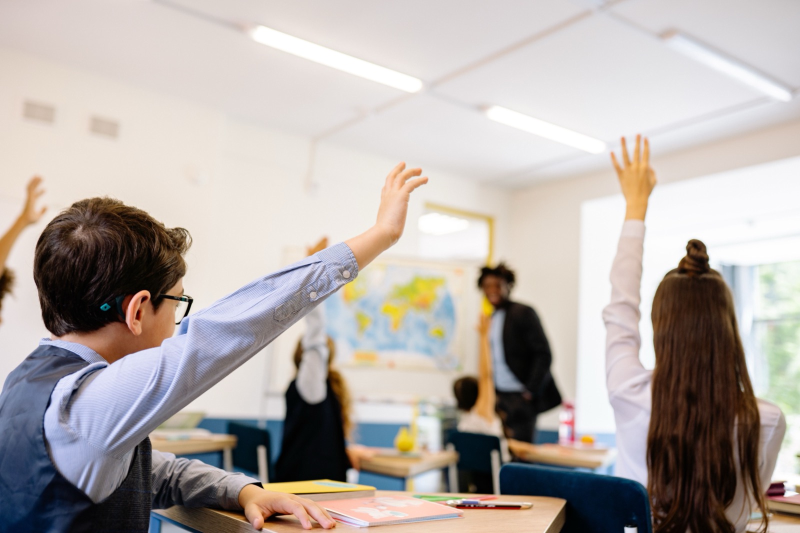 Students in the classroom enthusiastically raising their hand
